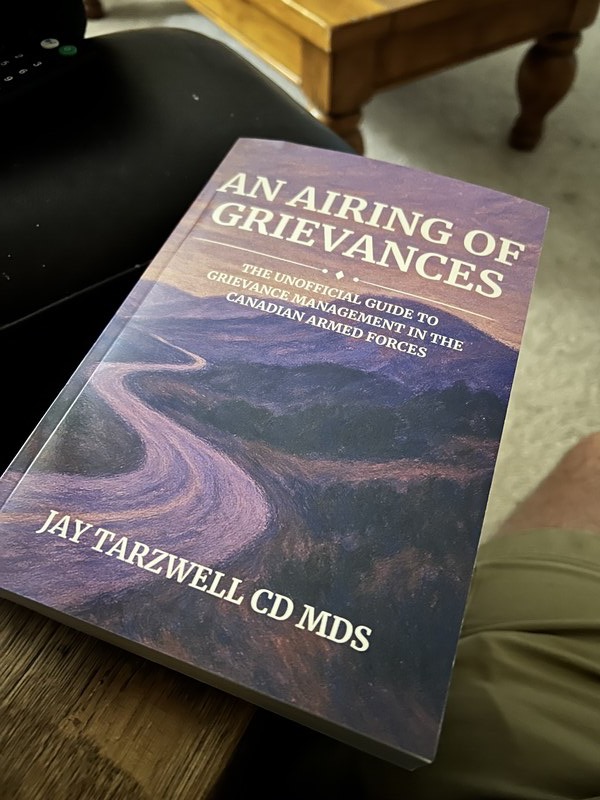 Jay Tarzwell holding An Airing of Grievances paperback book